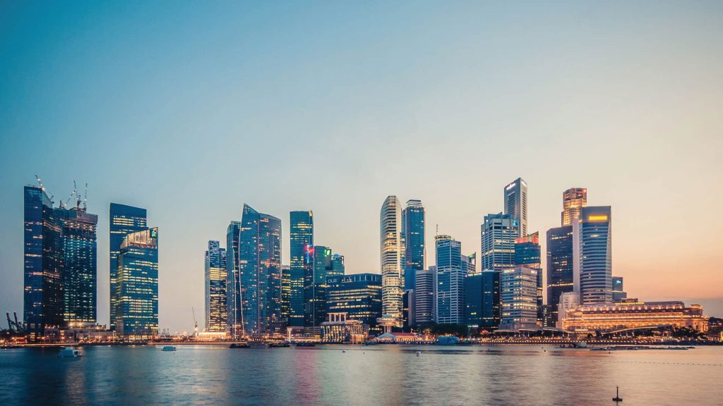 Skyline of a modern city with skyscrapers by the waterfront at sunset.